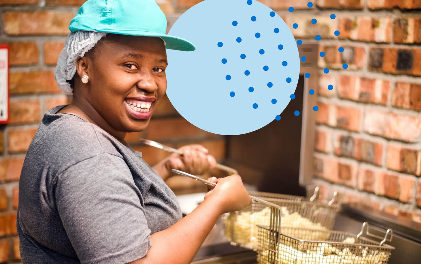 Female fast food worker putting french fries into a deep fryer at a fast food restaurant